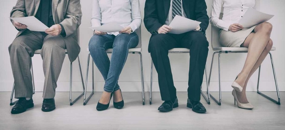 Four people sitting in chairs, only their chest to feet are visible.