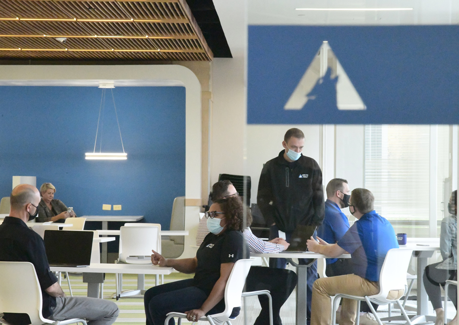Employees working in a shared office space, spread out and wearing masks