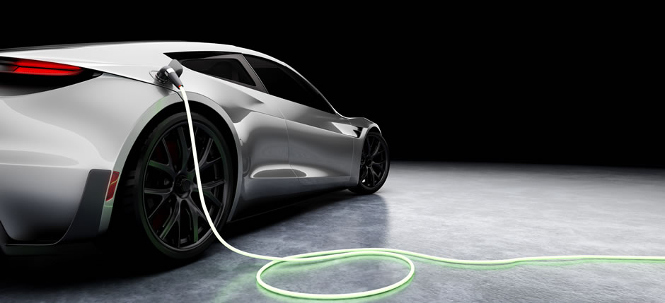 Une voiture sport électrique argentée en train d’être rechargée sur fond noir.