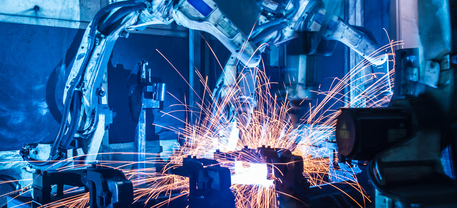 Two robotic arms in an industrial setting with sparks flying
