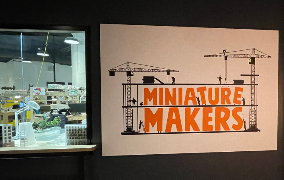 Une fenêtre exposée qui montre les maquettistes de Petit Canada au travail.