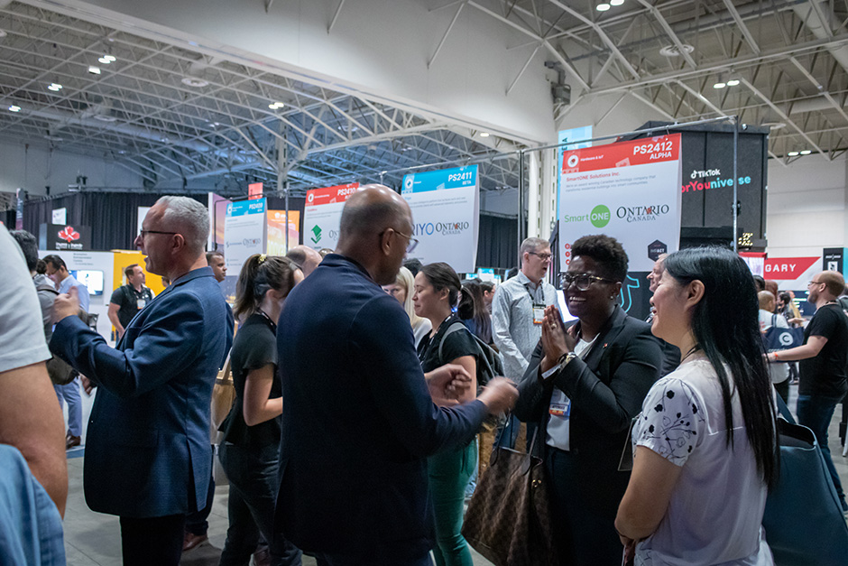 Among the Ontario booths, enthusiastic attendees and Ontario delegates smiling, gesturing, mingling and networking