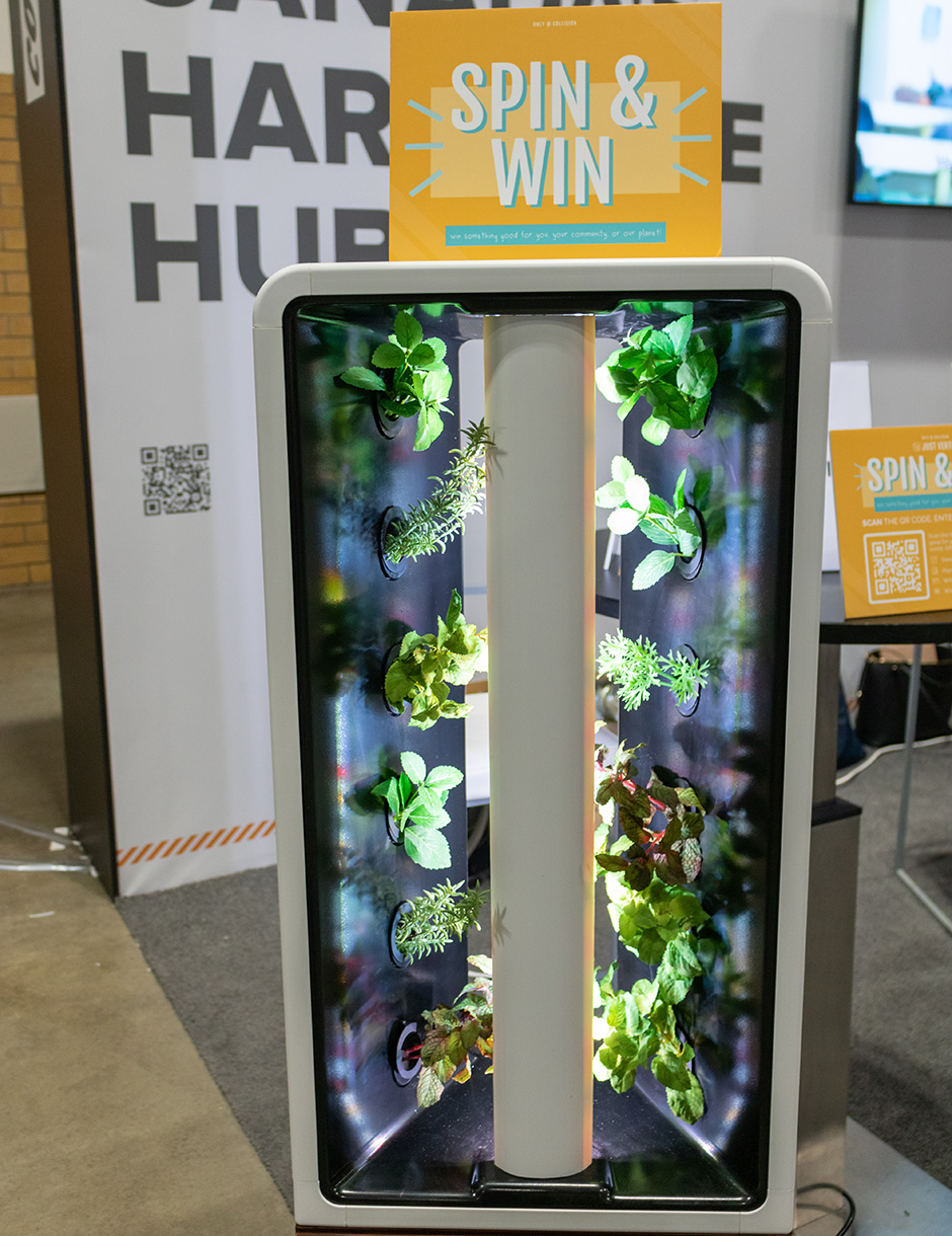 A stand-up rectangle frame with 6 plants stacked along each side and a light source in the middle