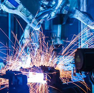 Deux bras robotiques dans un cadre industriel avec des étincelles volantes