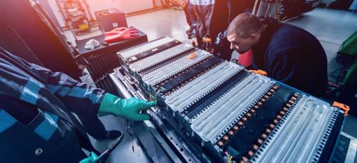 Workers charging the batteries of the electric motor and disassembling the battery of an electric vehicle engine.
